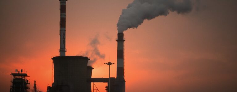 Fossil fuel power plant at sunset pumping out a huge plume of C02